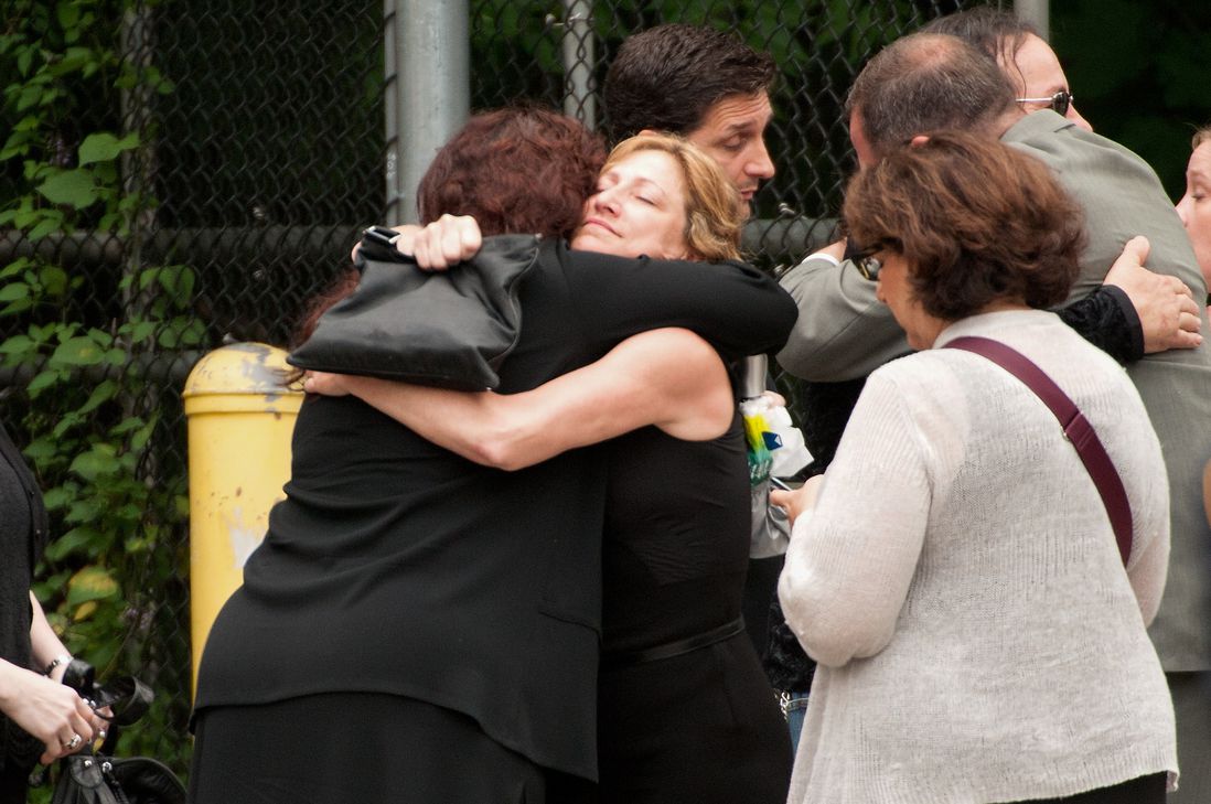 Edie Falco hugs another mourner